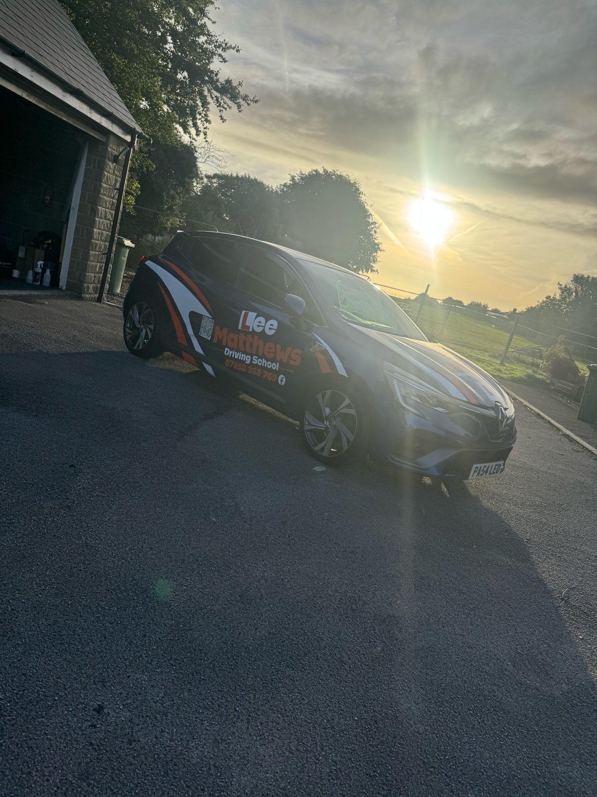 Dark Lee Matthews Driving School Clio outside the Glapwell unit in golden-hour light, glossy finish visible